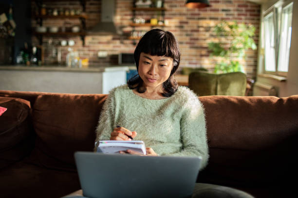 istock Young Japanese Woman using a laptop on a couch 1488400709
