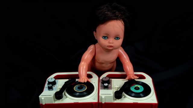 Plastic doll djing on toy record player.