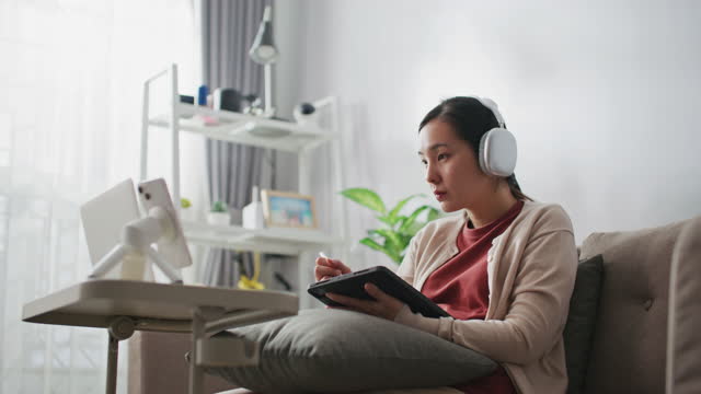 Young woman wearing headphones learning using computer and teleconferencing apps