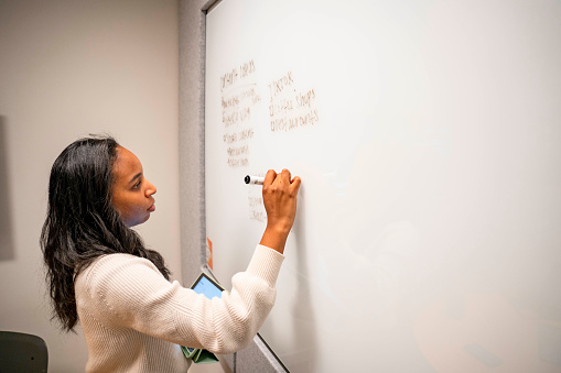 African American Woman writing on a whiteboard