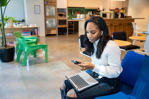 African American woman in coworking space using phone