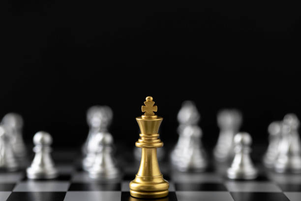 istock Golden King chess standing in front of other chess on chess board. 1488411372