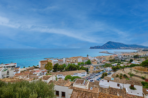 A small old town on the Mediterranean coast. View of the rooftops and the sea from the observation deck located on a hill. Mountains in the background. Altea. Spain.