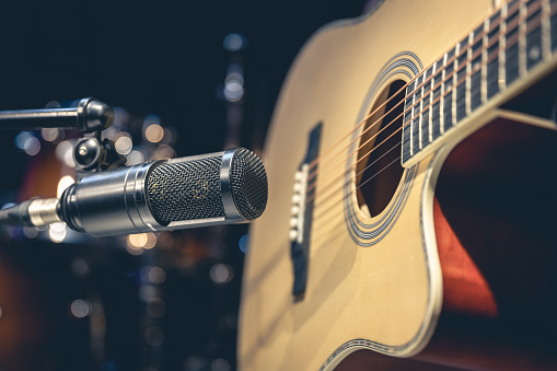 Acoustic guitar and microphone, close up, recording in a music studio.