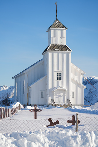 Snow covering White church and small cemetery in Gimsøy on Gimsoysand island in Lofoten archipelago, Nordland, Norway.