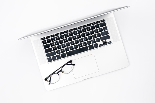 Minimalistic business background with laptop and glasses, top view.
