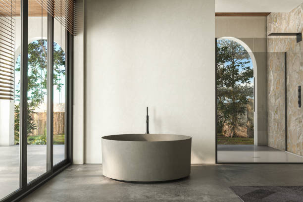 istock Modern bathroom featuring a natural stone countertop with an integrated sink, a round mirror, a shower cabin, a round bathtub, and a sleek concrete floor. The natural light, back yard. 3d rendering 1488415251