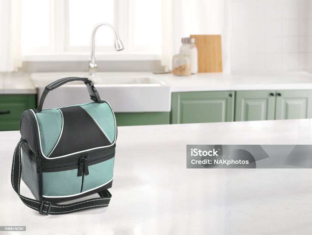 Lunch bag in a kitchen with a marble counter top. Lunch bag in a kitchen with a marble counter top and sink in the background Kitchen Counter Stock Photo