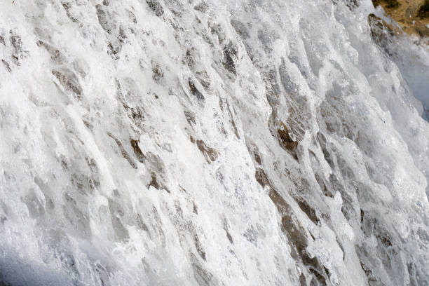 Close-up of bubbling water of cascade with white foam. Mountain river waterfall stream flows over mossy stones. Nature and natural beauty concept