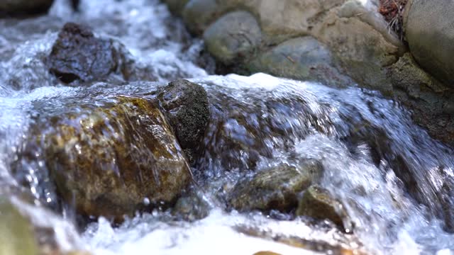 Rocks in a stream with smoothly flowing water close-up.