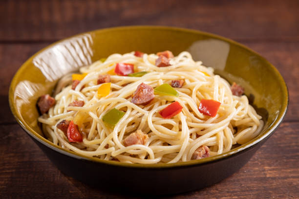 istock Plate with spaghetti, bacon and chopped vegetables. 1488418702