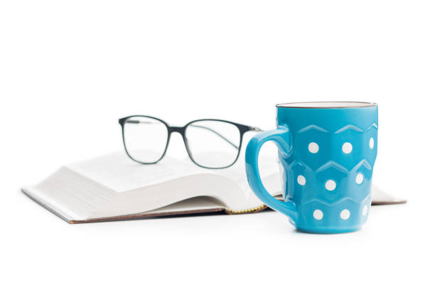 The polka dot mug with book and glasses isolated on the white background.