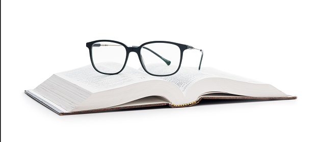 The reading glasses on opened book isolated on the white background.