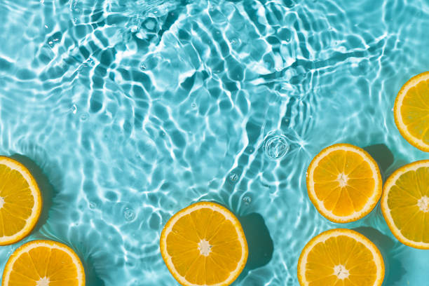 istock Creative summer background with orange fruit slices in swimming pool water. 1488424329