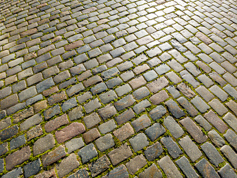 Granite dirty paving stones in the city. Road from paving stones for background and texture. The old road of granite paving stones.