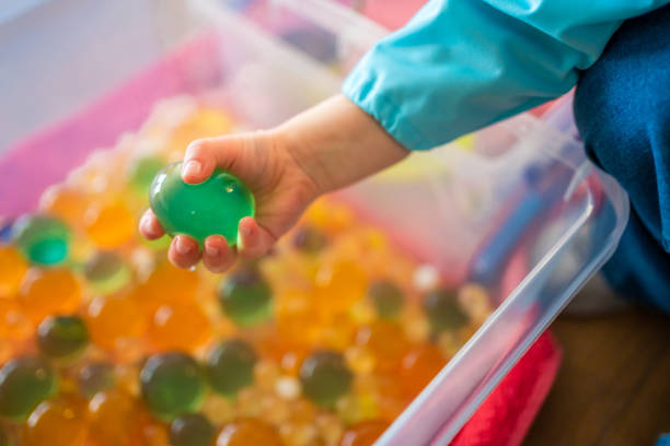 Little girl playing with sensory water beads, hydrogel balls. Sensory development and experiences, themed activities with children, fine motor skills development