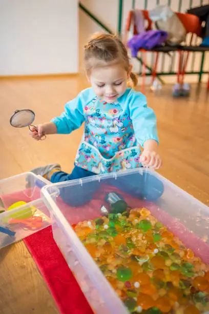 Little girl playing with sensory water beads, hydrogel balls. Sensory development and experiences, themed activities with children, fine motor skills development. High quality photo