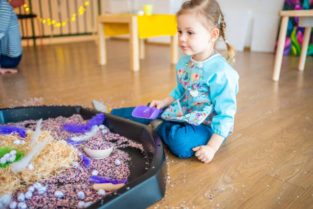 Little girl playing with sensory colorful rice. Sensory development and experiences, themed activities with children, fine motor skills development