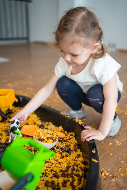 istock Little girl playing with sensory flakes in sandbox for playing. Sensory development and experiences, themed activities with children, fine motor skills development 1488427941