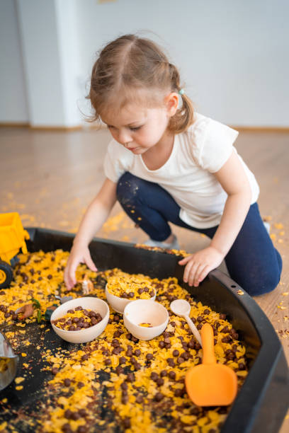 istock Little girl playing with sensory flakes in sandbox for playing. Sensory development and experiences, themed activities with children, fine motor skills development 1488427969