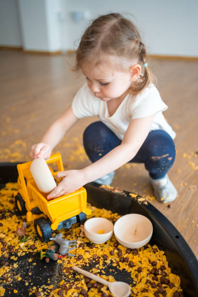 istock Little girl playing with sensory flakes in sandbox for playing. Sensory development and experiences, themed activities with children, fine motor skills development 1488427979