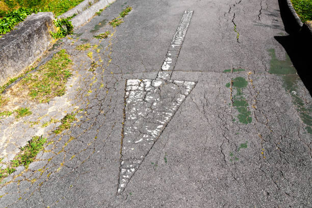 flèche inverse sur une route asphaltée altérée - tire track arrow sign road street photos et images de collection