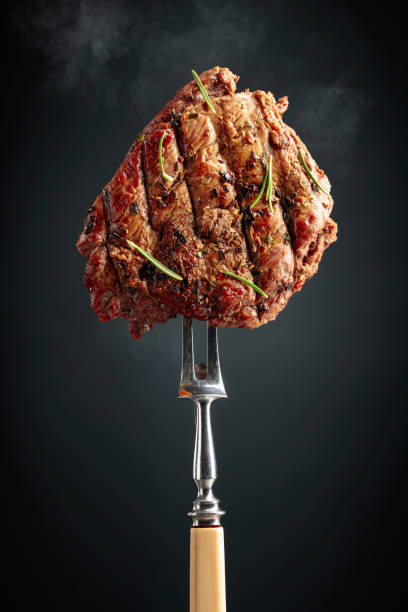 istock Grilled beef steak on a fork sprinkled with rosemary. 1488430301