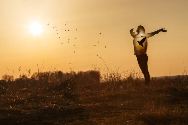 Concept of happiness and hope. Woman on the background of a sunny sunset with a dove inside.