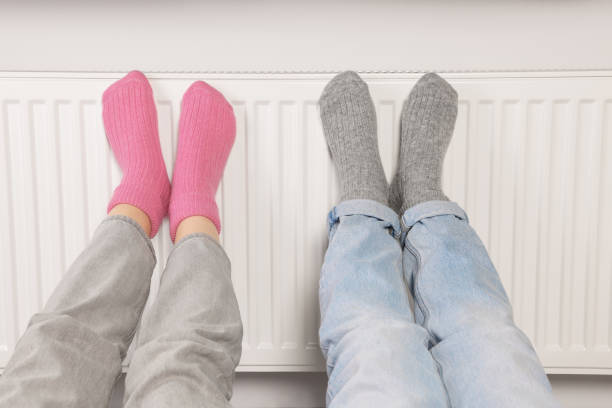 istock People warming feet near heating radiator, closeup 1488432847