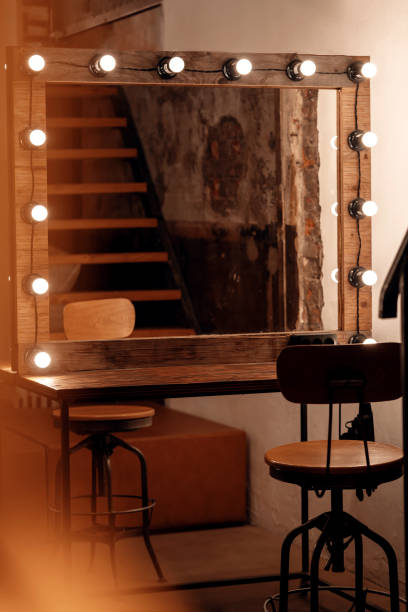 Dressing table and mirror with lamp bulbs in vintage make-up room. Dressing table and mirror with lamp bulbs in retro style make-up room. Vintage building interior concept with copy space. theatre mirror stock pictures, royalty-free photos & images