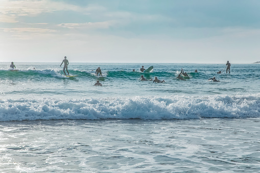 Arrifana, Aljezur, Portugal. 09. 29. 2020.Silhouette Of surfer people on sunset beach catch oceans wave. Surfing sport wellness and travel concept.