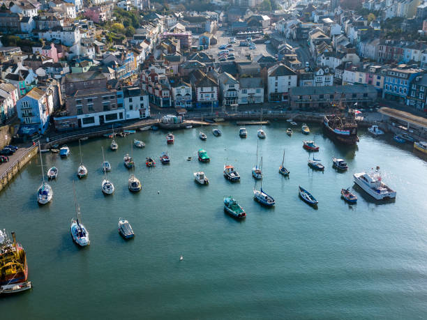 Aerial drone view of Brixham harbour in Devon, with moored small sailing and motor boats.  The town has a thriving fishing industry and is a popular tourist destination.