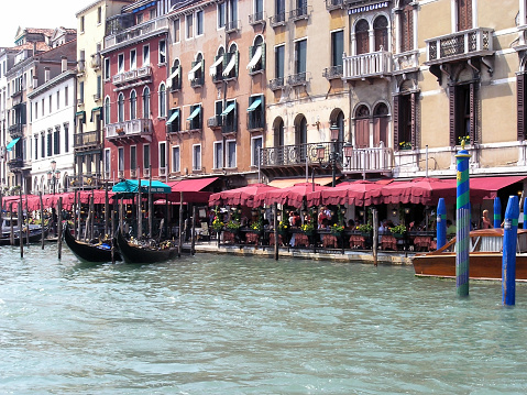 Near the old houses of the pier with gondolas on the water and restaurants in Venice, Italy. Historical tourist attraction of the Middle Ages