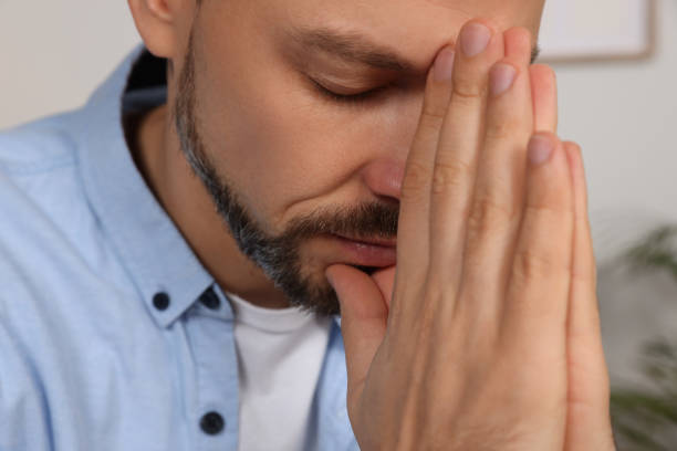 istock Man with clasped hands praying indoors, closeup 1488438560