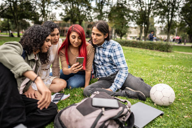 istock Student friends watching something on a mobile phone in the public park 1488438699