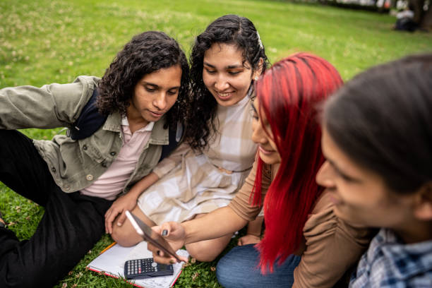 istock Student friends watching something on a mobile phone in the public park 1488438703