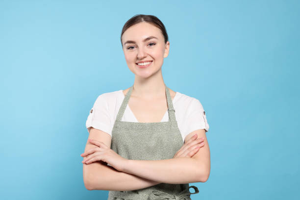 istock Beautiful young woman in clean apron with pattern on light blue background 1488439448