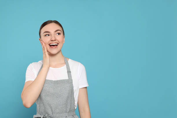 istock Beautiful young woman in clean apron with pattern on light blue background. Space for text 1488439464