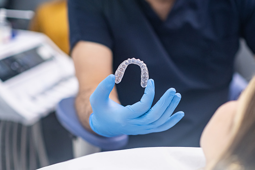 Professional orthodontist showing innovative aligners designed for bite correction to camera doctor in rubber gloves demonstrates modern transparent caps for teeth