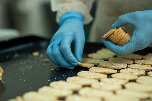 A woman employee arranging crackers on a tray in a bakery.