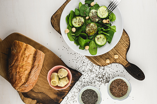 green spinach with vegetables and bread on a cutting board.