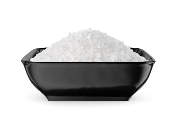 istock Coarse sea salt in black square bowl isolated on white. Front view. 1488446395