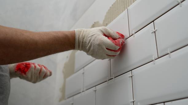Workers lay ceramic tiles on the kitchen wall. Construction details, repair work. Tiles in the kitchen, the master glues. stock photo