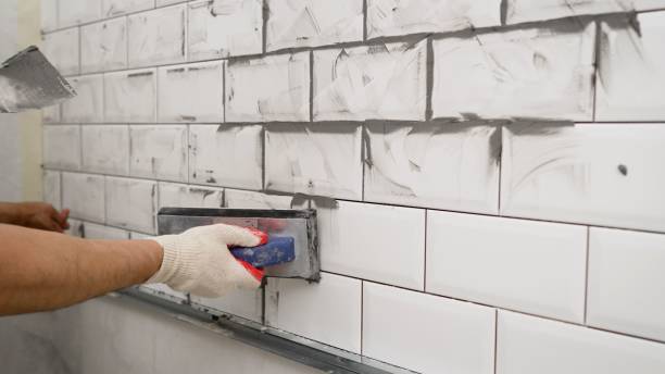 White tile in the kitchen with gray grout. The process of applying grout to ceramic tiles. Small ceramic tiles. Black grout for white ceramic tiles. stock photo