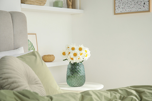 Bouquet of beautiful daisy flowers on table in bedroom