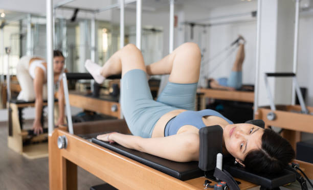 istock Positive woman doing lower back exercises while lying on Pilates bed in wellness center 1488450794