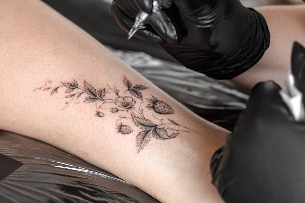 Tattoo master protective gloves make a tattoo in black ink on the hand of the girl. Close-up.
