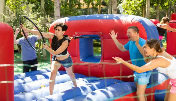Photo of Cheerful woman having funny competition in collect of hoops on inflatable trampoline