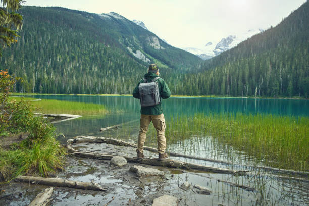 istock Active tourist with backpack standing at mountain lake and wood background 1488453173