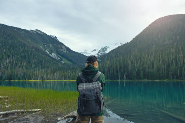 istock Active tourist with backpack standing at mountain lake and wood background 1488453189